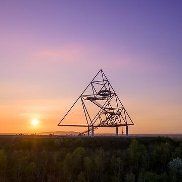 Tetraeder aus Stahl auf einer begrünten Halde bei Sonnenuntergang