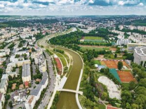 Renaturierter Fluss durch eine dicht bebaute Stadt mit viel Grün und Sportplätzen