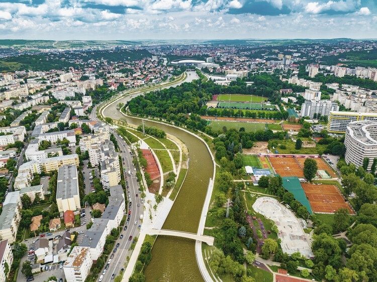 Renaturierter Fluss durch eine dicht bebaute Stadt mit viel Grün und Sportplätzen
